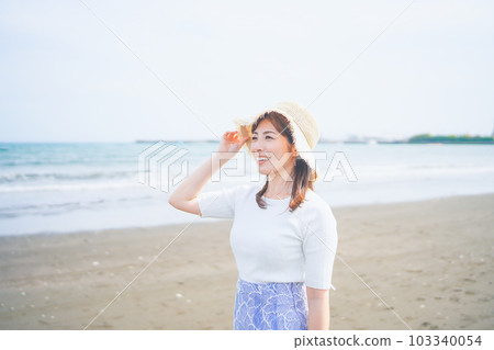 Smiling woman wearing a straw hat by the sea 103340054