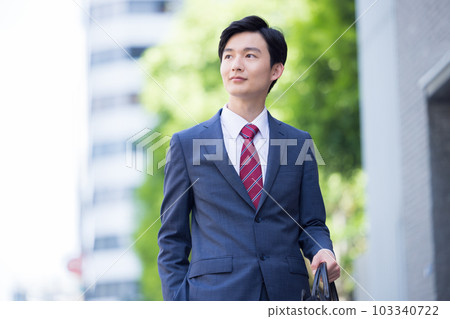一個年輕的商人在戶外散步 一個年輕的商人在戶外散步 103340722