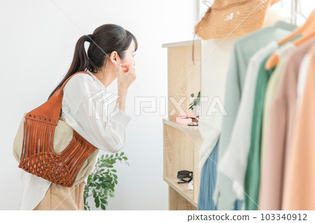 一位女性顧客在飾品店/雜貨店挑選穿孔耳環 一位女性顧客在飾品店/雜貨店挑選穿孔耳環 103340912