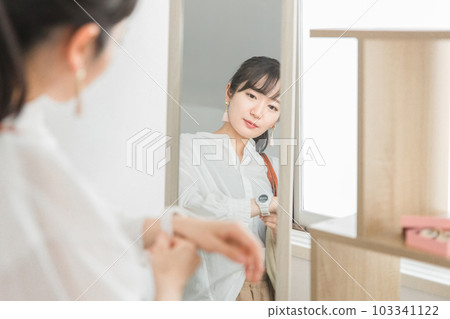 A female customer looking through the mirror choosing a wristwatch at an accessory shop/general store A female customer looking through the mirror choosing a wristwatch at an accessory shop/general store 103341122