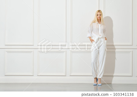 Beautiful woman in white shirt and trousers indoors 103341138