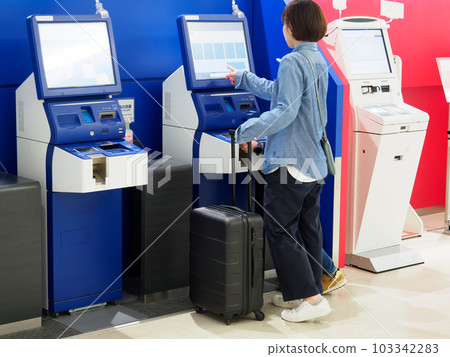 Back view of a woman operating an automated check-in machine at the airport Back view of a woman operating an automated check-in machine at the airport 103342283