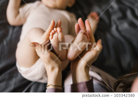 Baby feet in the hands of the mother. Tiny legs of a newborn baby on female hands close-up. Baby feet in the hands of the mother. Tiny legs of a newborn baby on female hands close-up. 103342380