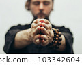 Fingers pointing forward to the camera. Hands folded in prayer. Close-up of palm together. The beads on the wrist. The rosary on hand. 103342604