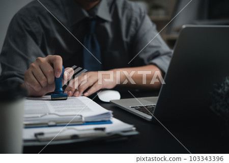 Man hand stamping approval signing on document or paperwork contract at desk. Man hand stamping approval signing on document or paperwork contract at desk. 103343396