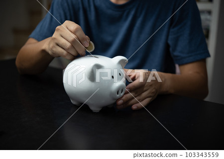 Man holding coin in white piggy bank, investment, finance, banking, savings and retirement concept Man holding coin in white piggy bank, investment, finance, banking, savings and retirement concept 103343559