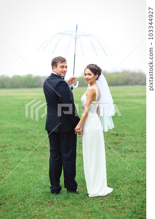 bride and groom on a rainy wedding day walking 103344927