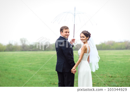 bride and groom on a rainy wedding day walking 103344929