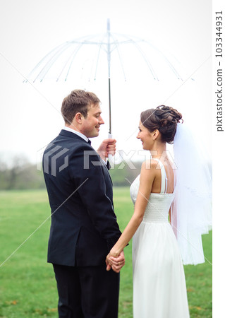 bride and groom on a rainy wedding day walking bride and groom on a rainy wedding day walking 103344931