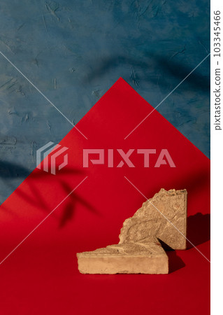 Rock stand. Product showcase. Beige cracked stone pieces arrangement leaves shadow on red blue paper cut color block decorative abstract background with free space. 103345466
