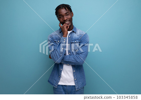 pensive brunette man with dreadlocks in a denim jacket on a blue background pensive brunette man with dreadlocks in a denim jacket on a blue background 103345858