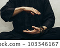 A man in black shirt sitting and doing qigong. Hands direct energy. Prayer, gratitude.Practicing monk. Qi energy. Yoga pose. Close up 103346167