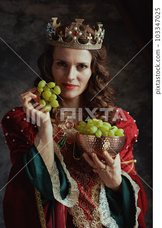 medieval queen in red dress with plate of grapes and crown medieval queen in red dress with plate of grapes and crown 103347025