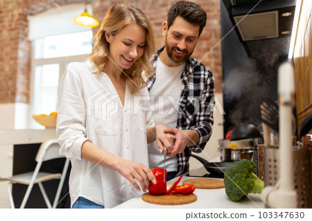 Loving young couple cutting vegetables at kitchenn counter. Loving young couple cutting vegetables at kitchenn counter. 103347630