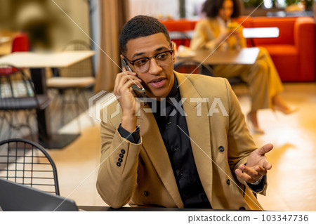 Young businessman having a call while waiting for a room in a hotel Young businessman having a call while waiting for a room in a hotel 103347736