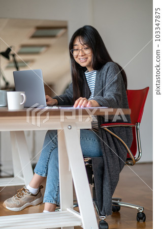 Long-haired asian young woman working in her home office 103347875