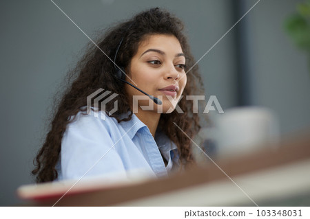 Smiling businesswoman or helpline operator with headset and computer at office 103348031