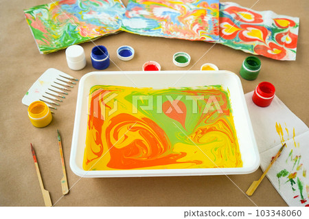 abstract drawing Ebru and set of tools on table. Traditional Turkish Ebru technique. top view. Children development concept abstract drawing Ebru and set of tools on table. Traditional Turkish Ebru technique. top view. Children development concept 103348060