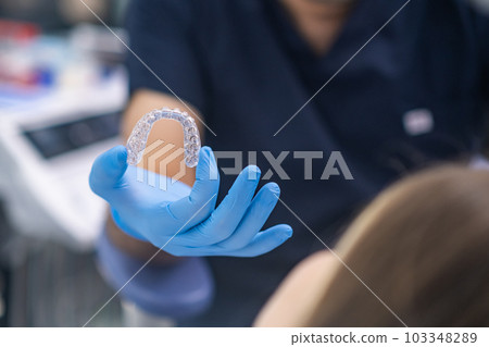Bite correction in modern dentistry clinic closeup of orthodontist showing female patient transparent aligners designed for teeth alignment woman at dental appointment Bite correction in modern dentistry clinic closeup of orthodontist showing female patient transparent aligners designed for teeth alignment woman at dental appointment 103348289