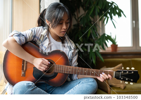 Cute young asian girl with guitar at home Cute young asian girl with guitar at home 103348500