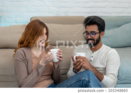Romantic couple drinking coffeee at home relaxing in cosy living room. Romantic couple drinking coffeee at home relaxing in cosy living room. 103348665