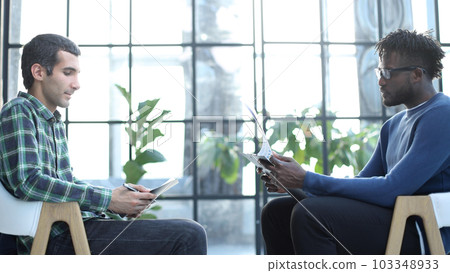 businessmen fill out a questionnaire while sitting side by side in a modern business hall 103348933