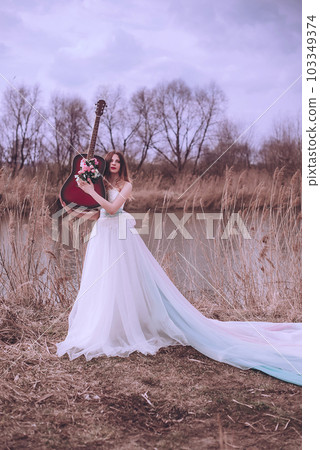 Beautiful romantic european girl with guitar with flowers inside, posing outdoors. Concept of music and nature. Spring time. Beautiful romantic european girl with guitar with flowers inside, posing outdoors. Concept of music and nature. Spring time. 103349374