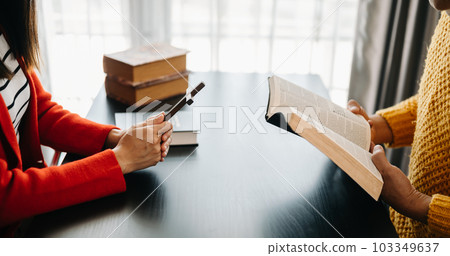 Two people reading and study bible in home and pray together.Studying the Word Of God With Friends.. 103349637