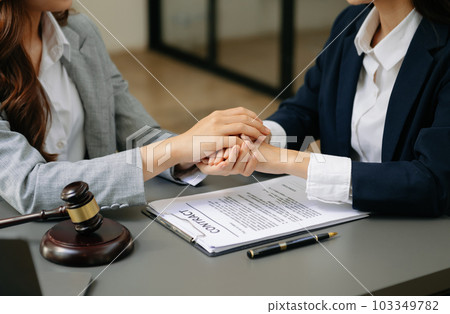 Business people compassionately holding hands and discussing contract papers with laptop and tablet at office 103349782
