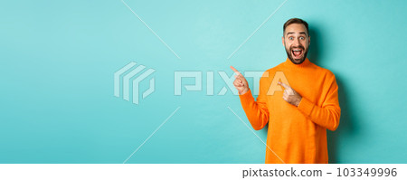 Excited man showing amazing promo offer, pointing fingers left at copy space on turquoise background Excited man showing amazing promo offer, pointing fingers left at copy space on turquoise background 103349996