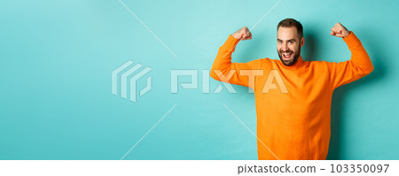 Young and strong man looking confident, flex biceps and show-off muscle strengths, smiling self-assured, standing over light blue background Young and strong man looking confident, flex biceps and show-off muscle strengths, smiling self-assured, standing over light blue background 103350097