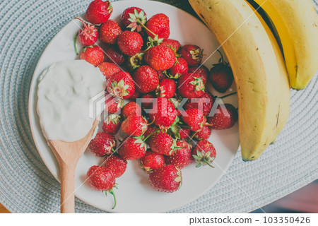 Bunch of bananas and strawberries. Photo toned style Instagram filters. Concept of healthy breakfast Bunch of bananas and strawberries. Photo toned style Instagram filters. Concept of healthy breakfast 103350426