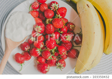 Bunch of bananas and strawberries. Photo toned style Instagram filters. Concept of healthy breakfast Bunch of bananas and strawberries. Photo toned style Instagram filters. Concept of healthy breakfast 103350432