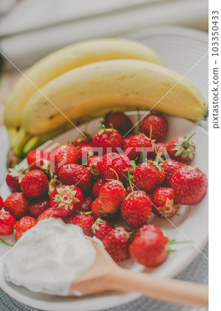 Bunch of bananas and strawberries. Photo toned style Instagram filters. Concept of healthy breakfast Bunch of bananas and strawberries. Photo toned style Instagram filters. Concept of healthy breakfast 103350433