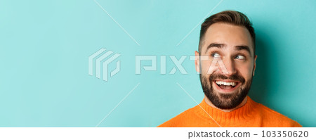 Headshot of handsome caucasian man looking at upper left corner logo and smiling pleased, checking out promo offer, standing over turquoise background Headshot of handsome caucasian man looking at upper left corner logo and smiling pleased, checking out promo offer, standing over turquoise background 103350620