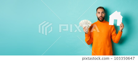 Real estate concept and mortgage concept. Amazed buyer holding money and paper house maket, buying apartment, standing over light blue background 103350647