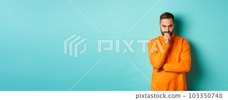 Thougtful young man making decision, looking serious and thinking, choosing, standing near copy space turquoise background 103350748