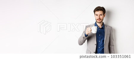 Handsome businessman in suit drinking coffee or tea from office mug, standing against white background 103351061