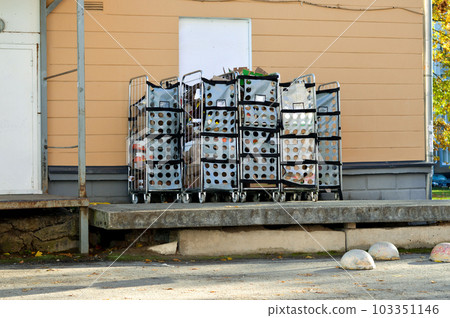 pallet and trash in plastic garbage bags and paper boxes near a building wall on a city street. 103351146