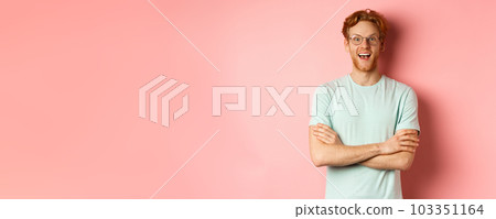 Portrait of cheerful european man in glasses looking amazed at camera, see interesting promotion, standing amused over pink background 103351164