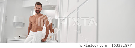 Attractive man near cabinet in contemporary spa salon with massage couch before procedures 103351877