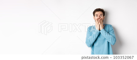 Shocked and startled cauacasian man, gasping and covering mouth with hands, staring at something scary, standing over white background Shocked and startled cauacasian man, gasping and covering mouth with hands, staring at something scary, standing over white background 103352067