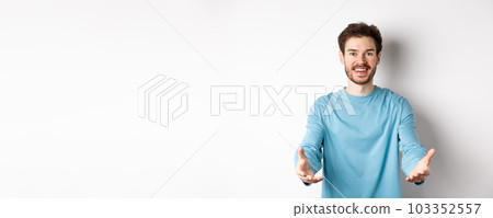 Attractive caucasian guy in casual clothes stretch out hands to hold something, receiving and smiling, standing over white background Attractive caucasian guy in casual clothes stretch out hands to hold something, receiving and smiling, standing over white background 103352557