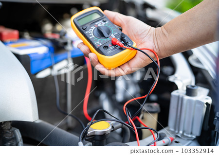 Asian auto mechanic check for repair under the hood of broken down car on the side of the road. 103352914