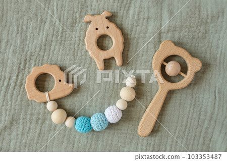 Wooden baby toys on green canvas background. Trendy eucalyptus color. Flat lay, copy space, top view. Sustainable early childhood development. Eco accessories, rattle and teethers for newborn Wooden baby toys on green canvas background. Trendy eucalyptus color. Flat lay, copy space, top view. Sustainable early childhood development. Eco accessories, rattle and teethers for newborn 103353487
