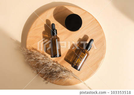 Amber glass bottle on beige background. Wooden branch. Natural skin care SPA beauty product design. Mineral organic oil cosmetics. Minimal Flat lay Amber glass bottle on beige background. Wooden branch. Natural skin care SPA beauty product design. Mineral organic oil cosmetics. Minimal Flat lay 103353518
