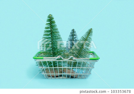 Small Christmas trees is in a shopping cart. Artificial mini Christmas tree in a supermarket trolley on blue background. Christmas, New Year, Holiday shopping concept. Minimalism Small Christmas trees is in a shopping cart. Artificial mini Christmas tree in a supermarket trolley on blue background. Christmas, New Year, Holiday shopping concept. Minimalism 103353678
