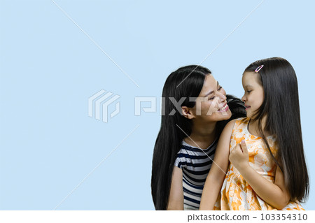 Portrait of a happy asian mother with her little daughter. Isolated on blue background. 103354310