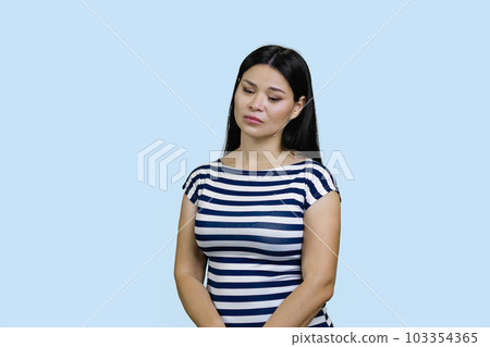 Sad asian woman standing upset and distressed. Isolated on blue background. Sad asian woman standing upset and distressed. Isolated on blue background. 103354365