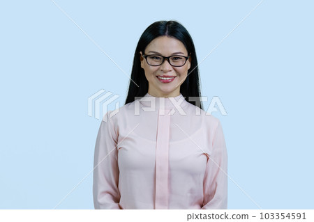 Portrait of happy young smart asian brunette woman in glasses. Isolated on pale blue background. 103354591